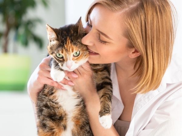 Woman cuddling cat, green eyes.